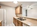 Kitchen features light countertops, wood cabinets, stainless steel sink and white refrigerator, combining functionality with style at 2231 S Vaughn Way # 205B, Aurora, CO 80014