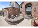 Inviting front patio with brickwork and seating area, leading to an arched doorway entrance on a sunny day at 10 Sand Cherry, Littleton, CO 80127