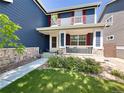 Inviting two-story home with blue siding, red shutters, a stone foundation, covered porch, and lush green lawn at 4049 S Quatar St, Aurora, CO 80018