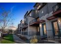 Modern townhome showcases stucco and stone exterior with private patio and sleek, black metal railings at 7928 E 54Th Pl, Denver, CO 80238