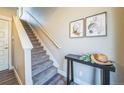 Stylish staircase features neutral carpet, modern art, and a sleek console table with elegant decor at 7928 E 54Th Pl, Denver, CO 80238