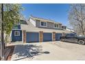 A row of townhomes featuring brick accents, blue garage doors, and a spacious parking area at 1351 S Cathay Ct # 102, Aurora, CO 80017