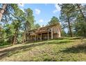 Expansive two-story home with a spacious deck overlooking a lush green lawn and surrounded by towering trees at 2235 Stonecrop Way, Golden, CO 80401