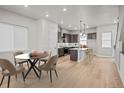 Open-concept kitchen and dining area with modern finishes, wood floors, and stylish lighting at 1727 W 166Th Ave, Broomfield, CO 80023