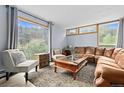 Bright living room featuring large windows offering scenic outdoor views, comfortable seating, and a stylish rug over wood floors at 11827 Brook Rd, Golden, CO 80403