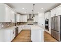 Bright kitchen featuring white cabinetry, stainless steel appliances, a herringbone backsplash, and a center island at 42964 Colonial Trl, Elizabeth, CO 80107