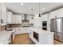 Bright kitchen featuring white cabinetry, stainless steel appliances, a herringbone backsplash, and a center island at 42964 Colonial Trl, Elizabeth, CO 80107