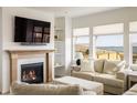 Cozy living room with a fireplace, large windows, and comfortable seating at 16568 W 92Nd Pl, Arvada, CO 80007