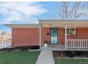 Inviting brick home featuring a cozy covered front porch with a blue door and fresh landscaping at 1476 W Dakota Ave, Denver, CO 80223