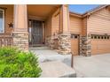 Inviting covered front porch with stone accents and wood railing, leading to a paneled front door at 23993 E Briarwood Dr, Aurora, CO 80016