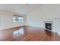 Bright living room boasts vaulted ceilings, a cozy fireplace, and gleaming hardwood floors at 23993 E Briarwood Dr, Aurora, CO 80016