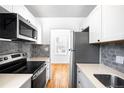 Modern kitchen featuring stainless steel appliances, white cabinetry, and stylish gray backsplash at 1168 Kearney St, Denver, CO 80220