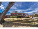 Well-maintained red brick home featuring a mature tree and manicured lawn at 6719 Quay St, Arvada, CO 80003