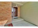 Covered front entrance to home, showcasing a classic brown front door and brick detailing at 1545 August Ln, Brighton, CO 80601
