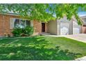 Brick and siding home with lush lawn, mature tree, and a welcoming front entrance at 1545 August Ln, Brighton, CO 80601