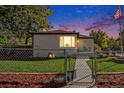 Twilight view of cozy single-story home with a fenced yard and a well-maintained lawn at 3790 W 54Th Ave, Denver, CO 80221