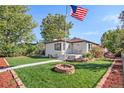 Inviting single-story home featuring a lush green lawn, mature trees, and an American flag at 3790 W 54Th Ave, Denver, CO 80221