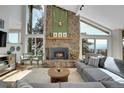 Bright living room with stone fireplace, cathedral ceilings, hardwood floors, and floor-to-ceiling windows at 1692 Sand Lily Dr, Golden, CO 80401