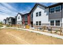 A row of well-maintained townhomes, each with distinct architectural details and fenced front yards at 2887 E 103Rd Dr, Thornton, CO 80229