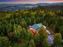Breathtaking aerial shot of a cozy house nestled amongst a dense forest of trees at 11163 Conifer Mountain Rd, Conifer, CO 80433