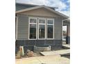 Close up of a two-story home with gray siding, large windows, light brown trim, and concrete base at 716 Belay St, Erie, CO 80516