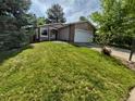 Inviting home with a well-manicured lawn and a two-car garage that has a beautiful stone accent wall at 2750 S Rifle St, Aurora, CO 80013