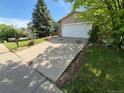 Charming home featuring a long driveway leading to a two-car garage, framed by mature trees and lush green lawn at 2750 S Rifle St, Aurora, CO 80013