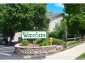 Well maintained Woodside community entrance sign with mature trees and manicured landscaping at 8555 Fairmount Dr # C202, Denver, CO 80247