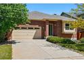 Classic brick home with a two-car garage and neatly maintained landscaping under a clear blue sky at 25077 E Canal Pl, Aurora, CO 80018