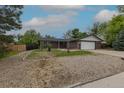 Inviting single-story home with a well-maintained lawn, an attached garage, and brick accents at 7042 W 76Th Ave, Arvada, CO 80003