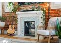Charming living room features exposed brick, a fireplace, and a cozy seating area with a guitar nearby at 3384 W 29Th Ave, Denver, CO 80211