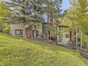 View of the condo backyard showing a grassy yard, mature trees, and fenced in outdoor patio spaces at 4912 Silver Spruce Ln, Evergreen, CO 80439