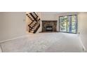 Spacious living room features new carpet, stone fireplace, sliding glass doors, and open staircase to upper level at 4912 Silver Spruce Ln, Evergreen, CO 80439
