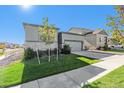 View of a charming home with a two car garage, well-manicured lawn, and a concrete sidewalk at 12724 Buffington Trl, Parker, CO 80134