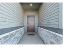 Inviting front porch area featuring a stylish front door, stone accents, and exterior lighting at 12724 Buffington Trl, Parker, CO 80134