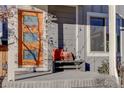 Inviting front porch with a bench and throw pillows, a pop of color with the orange front door and stylish lighting at 5863 N Boston St, Denver, CO 80238