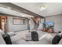 Finished living room features carpet, stairs, wooden beams, and plenty of natural light at 6190 Garrison St, Arvada, CO 80004