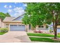 Charming brick home with a well-manicured lawn, a covered porch, and a two-car garage at 8225 W 67Th Pl, Arvada, CO 80004