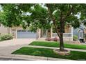 Charming brick home with a well-manicured lawn, a covered porch, and a two-car garage at 8225 W 67Th Pl, Arvada, CO 80004