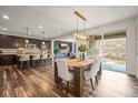 Open-concept dining room with hardwood floors, modern lighting, and a view of the backyard at 7875 S Grand Baker St, Aurora, CO 80016