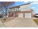 Brick townhouse exterior showcasing the entryway, two garage doors, and landscaping at 5537 Lewis Ct # 101, Arvada, CO 80002