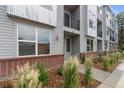 Street-level shot of modern gray townhomes with brick accents, green landscaping, and individual entrances at 8711 E Hampden Ave # 22, Denver, CO 80231
