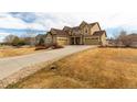 Tan two-story home featuring a long driveway and three-car garage at 3392 Homestead Dr, Longmont, CO 80504