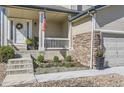 Inviting front porch with an American flag, landscaping, and stone accents adding to the home's curb appeal at 10487 Panther Trce, Lone Tree, CO 80124