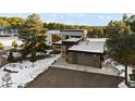 Modern home featuring a two-car garage, porte-cochere, and professional landscaping nestled amongst snow-covered trees at 367 Sandy Hollow Trl, Franktown, CO 80116