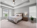 Bright main bedroom featuring a tray ceiling, large windows, and neutral décor at 15788 Xanthia Way, Thornton, CO 80602