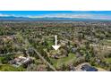 Aerial view of home surrounded by a canopy of trees with majestic mountains in the distance at 4480 S Franklin St, Cherry Hills Village, CO 80113