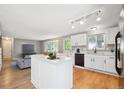 Open-concept kitchen featuring white cabinets, island, stainless appliances, and light wood flooring at 14625 Vine St, Thornton, CO 80602