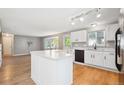 Bright kitchen featuring an island, white cabinets, stainless steel sink, and modern lighting at 14625 Vine St, Thornton, CO 80602
