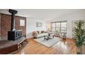 Cozy living room featuring hardwood floors, brick fireplace, and large window for natural light at 2393 E 90Th Ave, Thornton, CO 80229